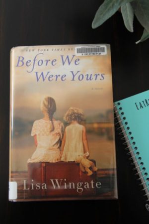 The book, Before We Were Yours, on a wood table with the cover facing up