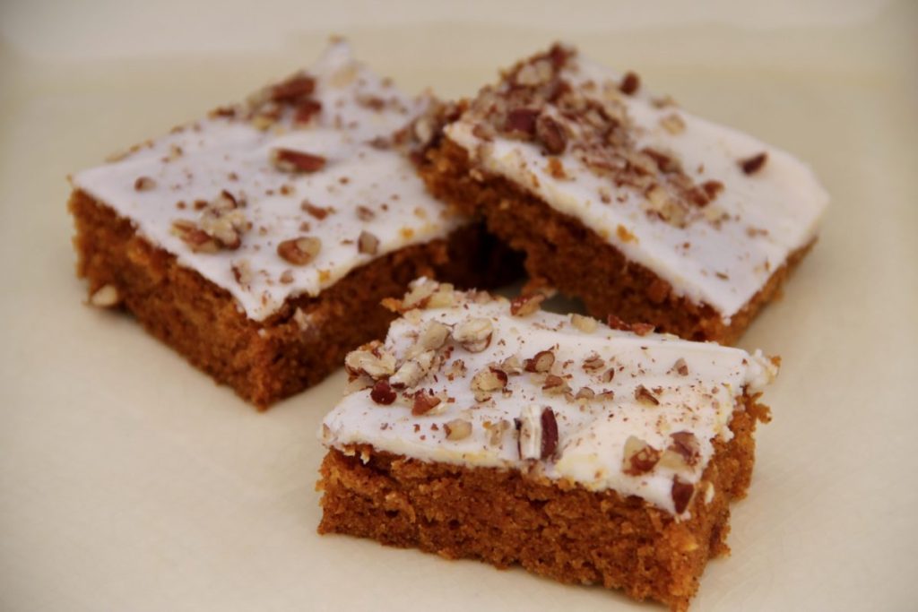 3 frosted carrot bars on a pale yellow ceramic plate