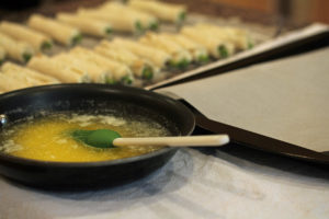 A small frying pan filled with melted butter ready to be brushed on the rolled asparagus appetizer.