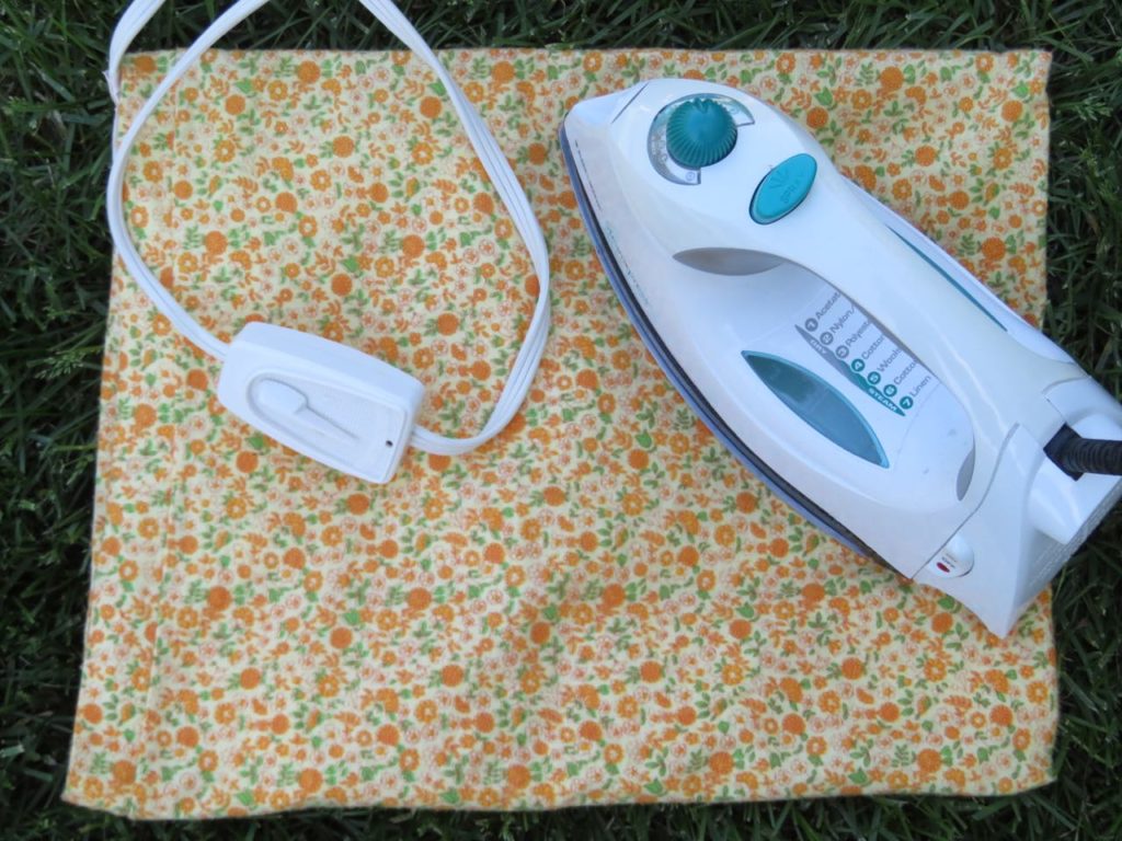 Heating pad with yellow flowered cover and a clothes iron