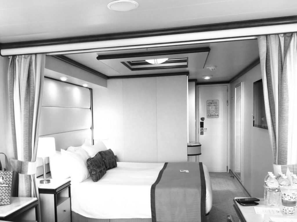 Black and white photo of a balcony room on the Royal Princess, showcasing the bed
