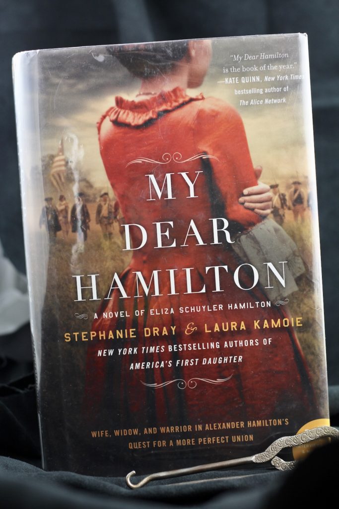 Hardbook of My Dear Hamilton: A Novel of Eliza Hamilton, with a black backhground and two antique metal shoe hooks leaning against the book