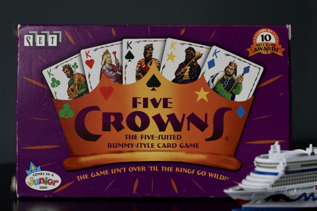 Five Crowns card game, on a counter with a small model cruise ship on the lower right side of photo