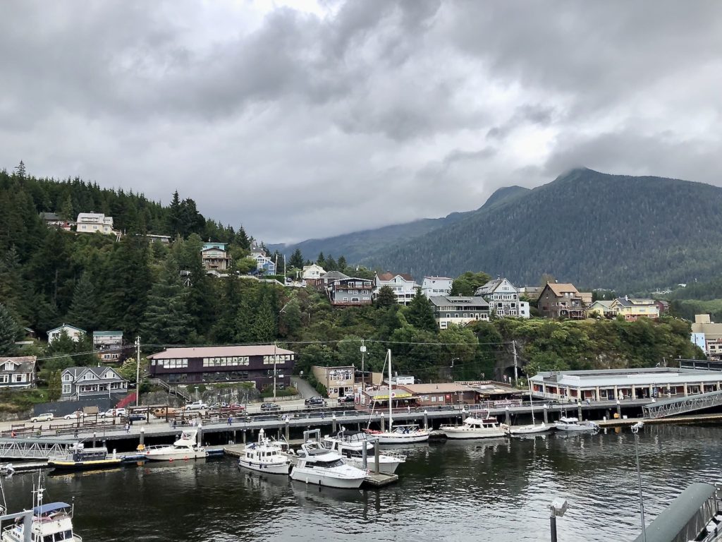 View of Skagway from cruise ship on an overcast day showing downtown and houses built on the mountain in back of town. Alaska cruise tips