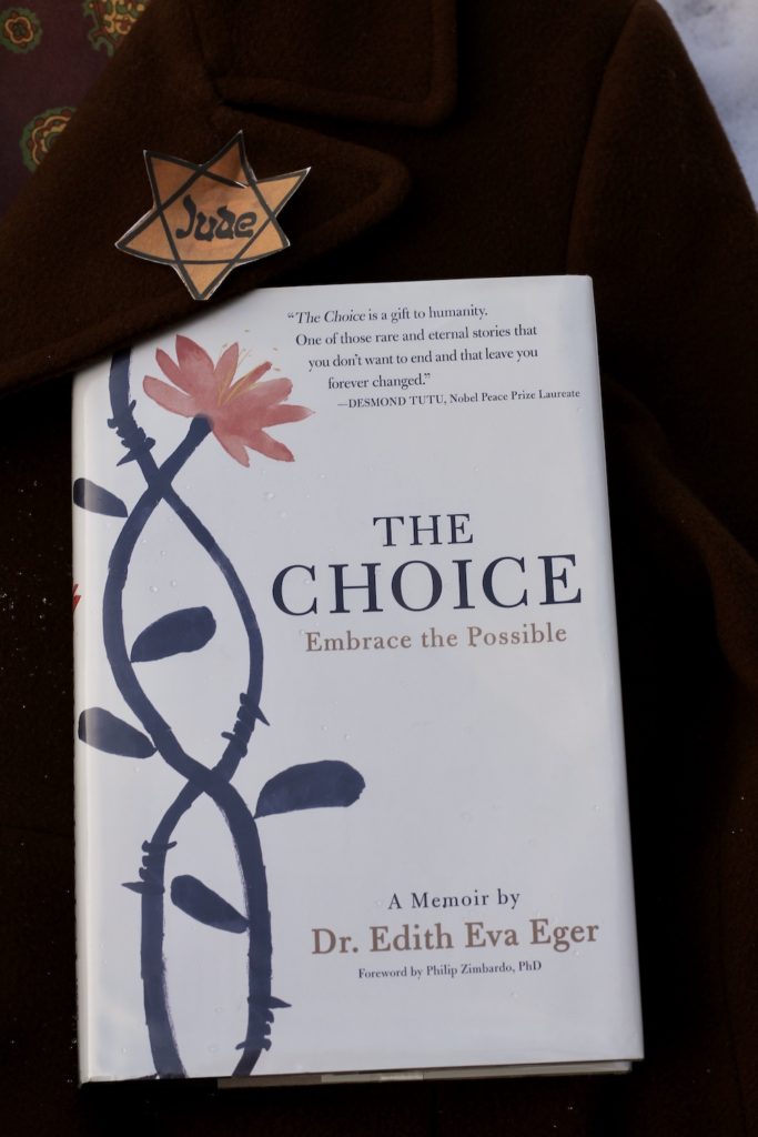 Hardcover of The Choice, laying on a brown wool winter woman's coat in the snow