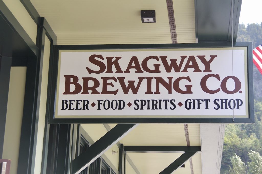 Skagway Brewing COmpany wood sign, white with red letters. A Day in Port: Skagway