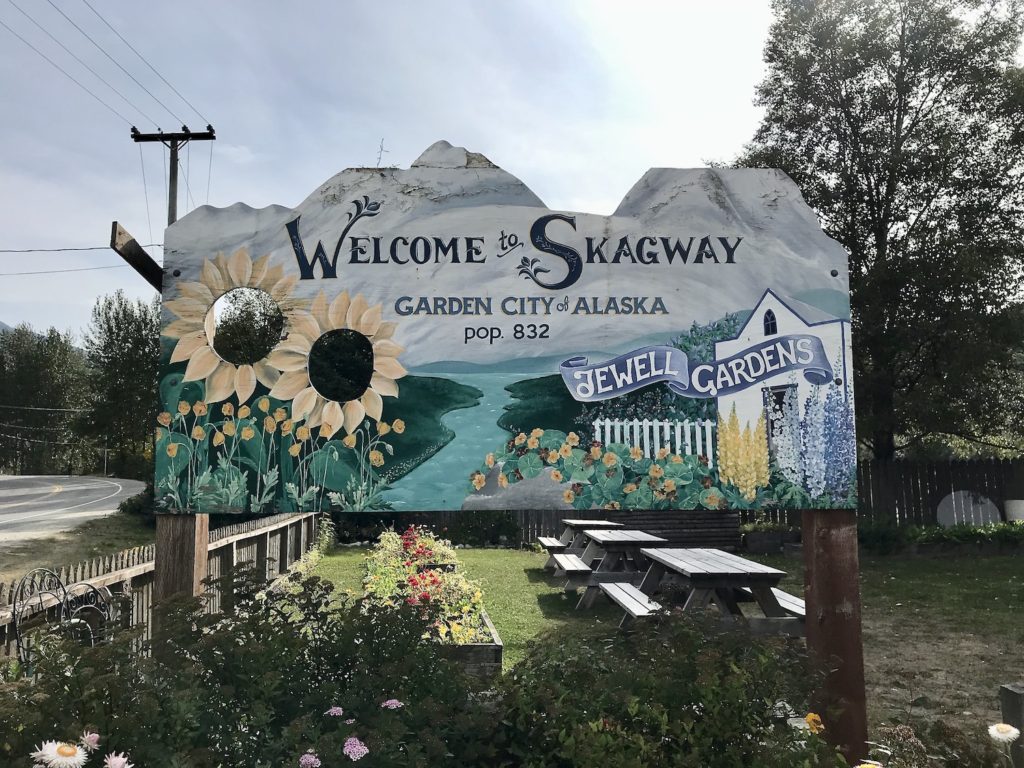 Welcome to Skagway wood sign with sunflowers, in front of the Jewell Gardens. 