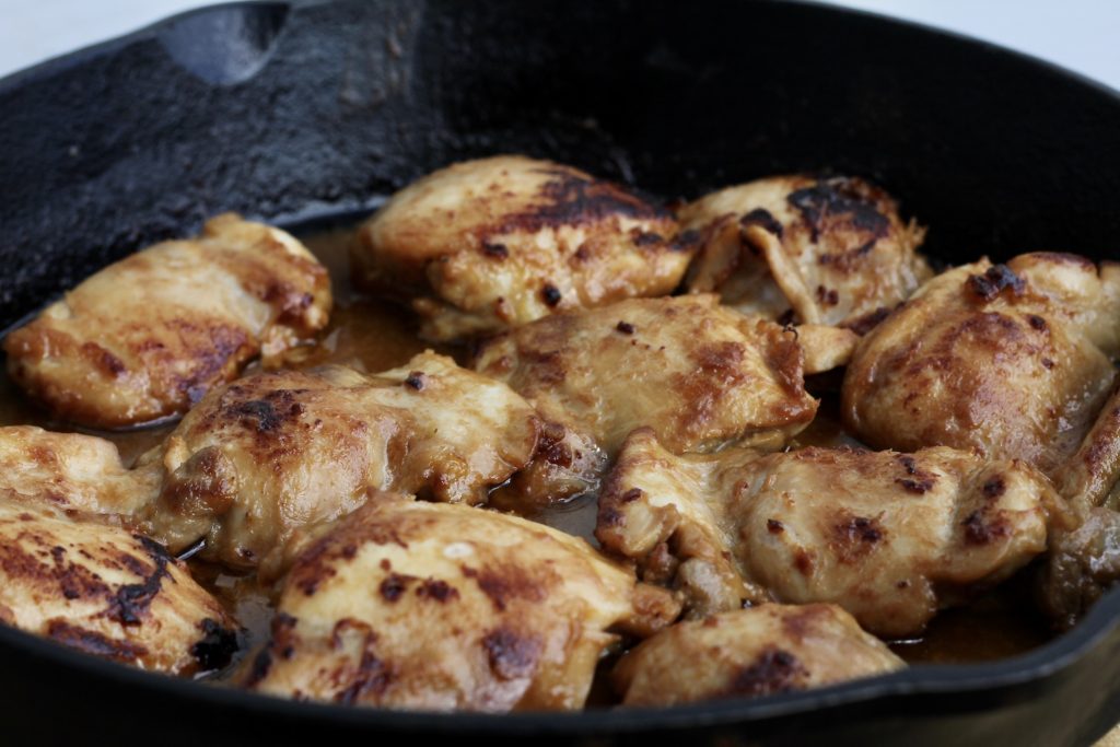 Chicken with Peanut sauce - chicken thighs browned in a cast iron skillet, with the peanut sauce on it, ready to finish in the oven